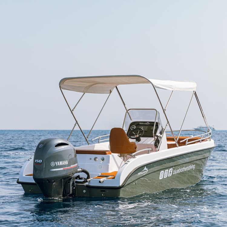 Small white motorboat with a Yamaha outboard engine on calm water.
