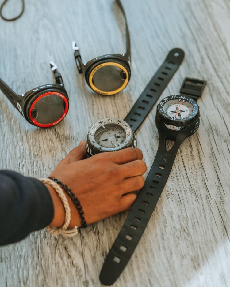 A collection of modern dive computers and watches displayed on a wooden surface.