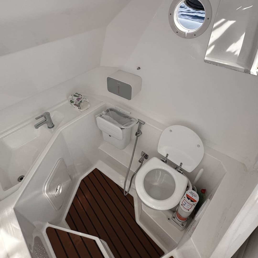 A compact and clean boat bathroom with a marine toilet and small sink.