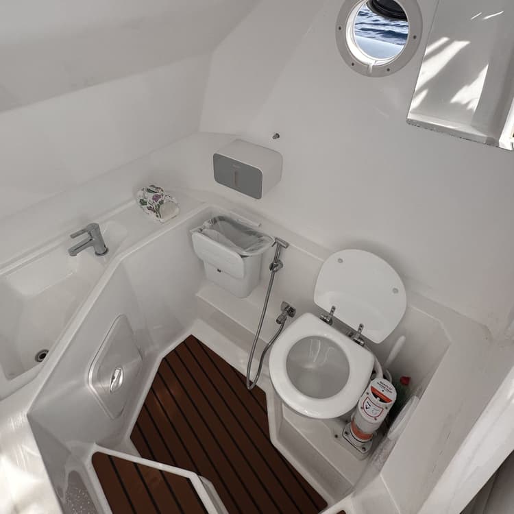 A compact and clean boat bathroom with a marine toilet and small sink.